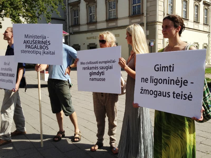 Sveikatos apsaugos ministerija ignoravo šeimų asociacijos prieš metus pateiktą prašymą spręsti gimdymo namuose reglamentavimo klausimą. Sigito Kondrato nuotraukoje - 2012 metų liepą vykęs piketas prie Sveikatos apsaugos ministerijos. Iš dg.lapas.info