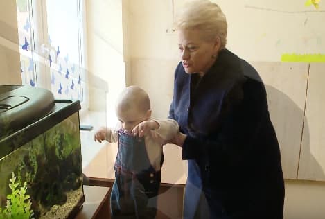 Prezidentė D. Grybauskaitė eilinės fotosesijos metu su vaiku rankose.